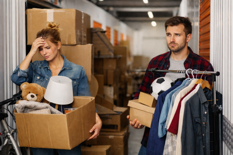 Para stojąca w magazynie self storage z kartonami i rzeczami podczas przeprowadzki